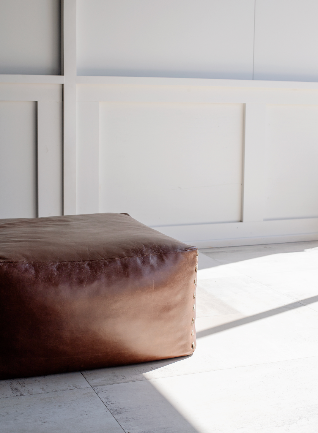 Brown leather ottoman with criss cross detail stitch