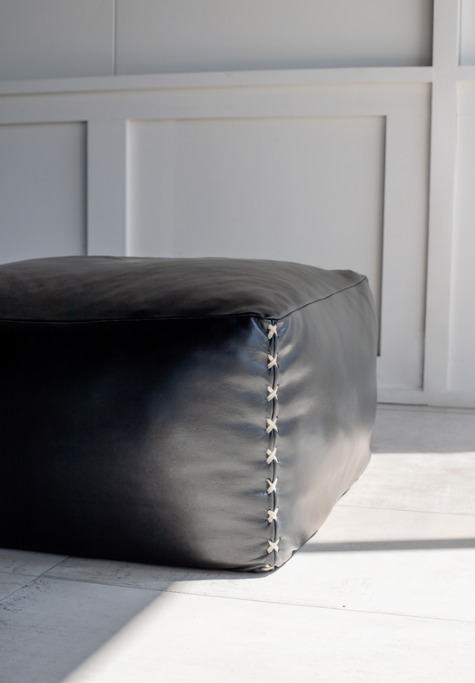 Black leather ottoman with criss cross detail stitch