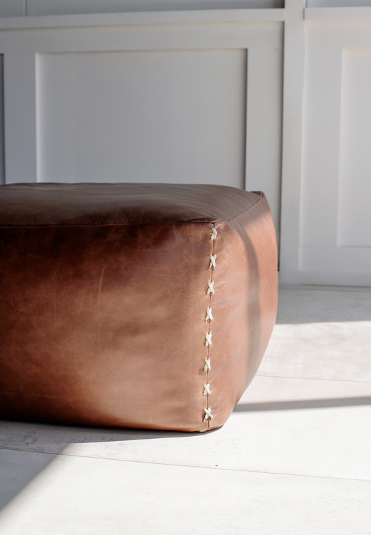 Brown leather ottoman with criss cross detail stitch